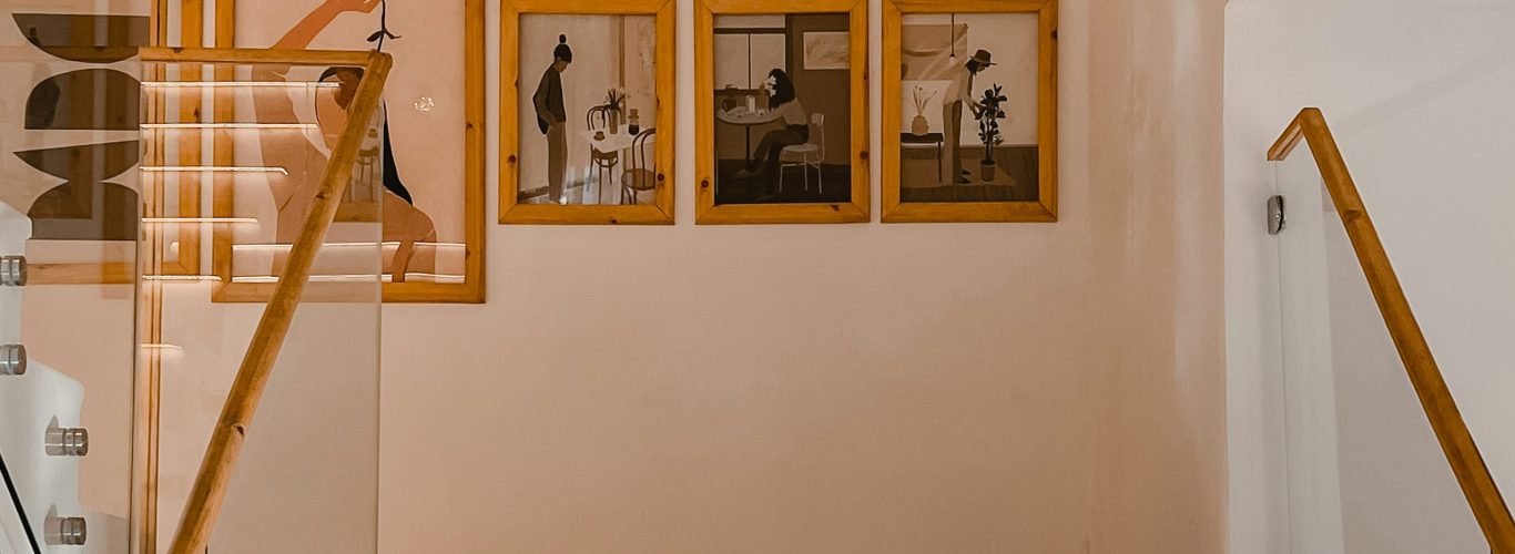 Staircase with wooden handrail and framed photographs on the wall.